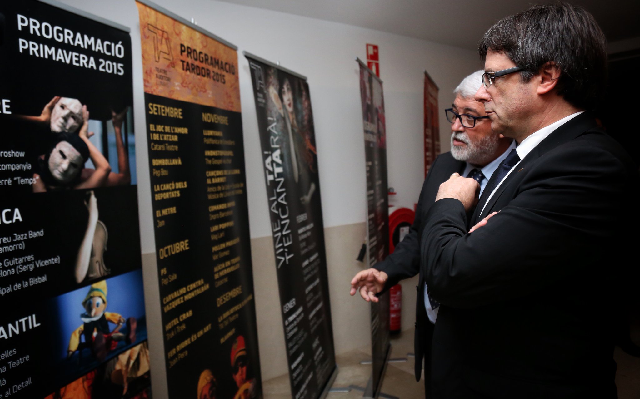 Puigdemont observa els cartells de les actuacions del teatre, acompanyat per l'alcalde, Martí Pujol