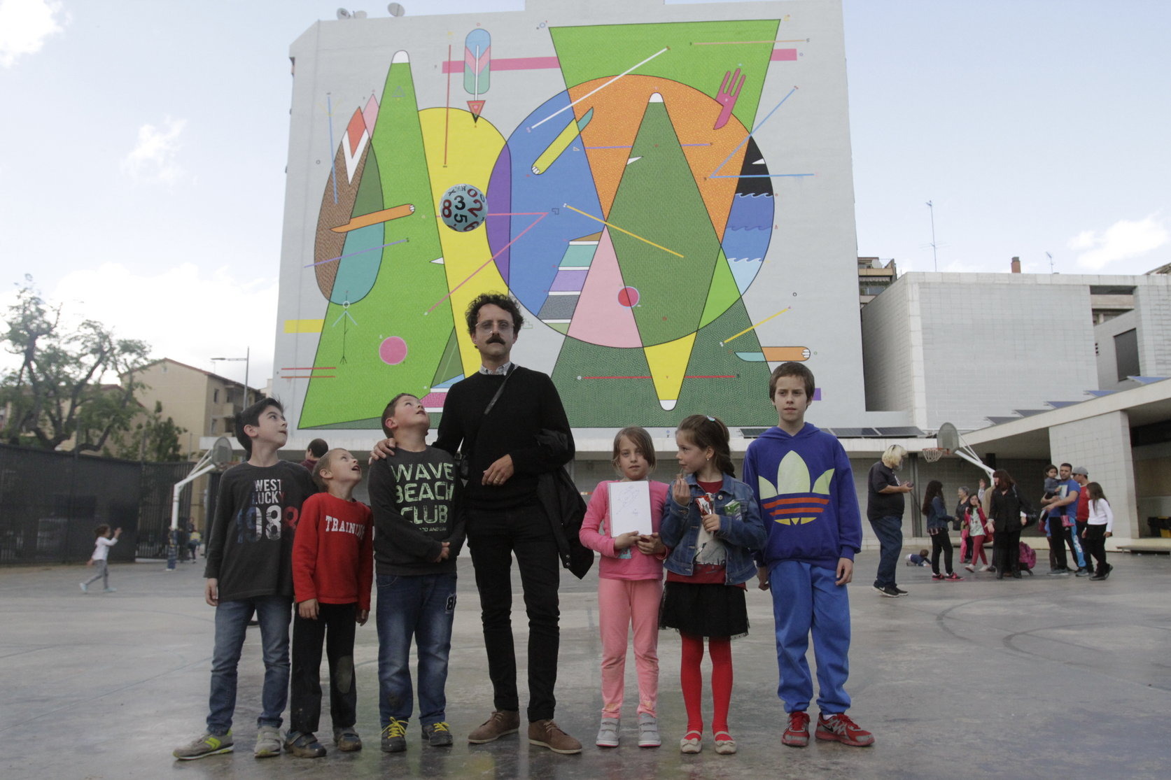 L'artista Sixe Paredes amb alguns dels alumnes de l'escola davant el mural