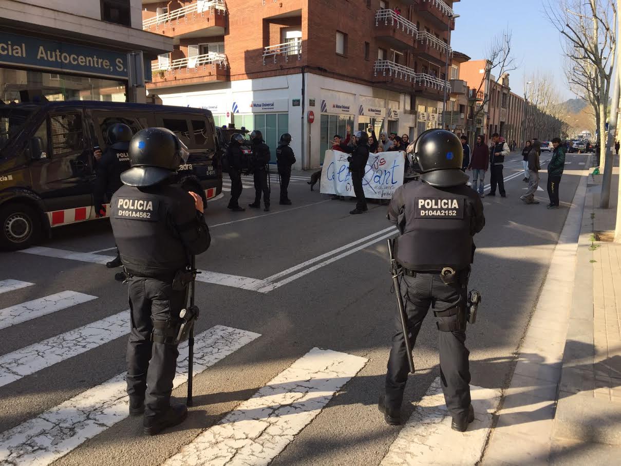 Agents dels Mossos controlen el carrer Prat de la Riba, mentre un grup de joves mostra el rebuig al desallotjament