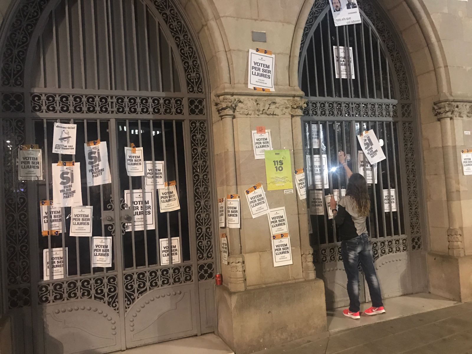 Una dona penjant cartells a la façana de l'Ajuntament de Granollers