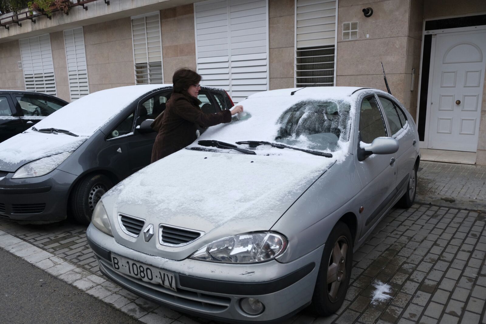 Una veïna retira la neu del seu cotxe al carrer Anselm Clavé, a la Garriga