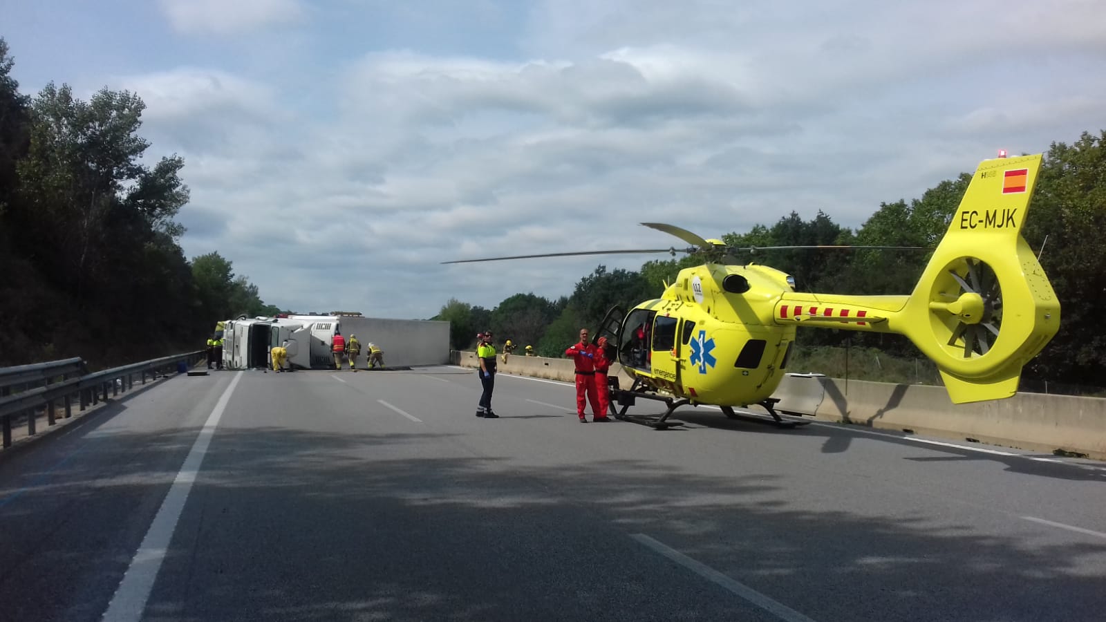 S'ha mobilitzat un helicòpter que ha traslladat al xofer a l'hospital. Al fons, el camió de fruita bolcat