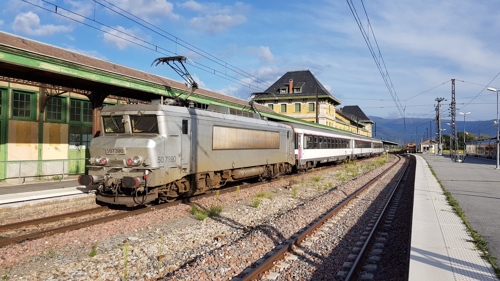 Un tren dels ferrocarrils francesos i un de Rodalies, al fons, a l'estació de La Tor de Querol