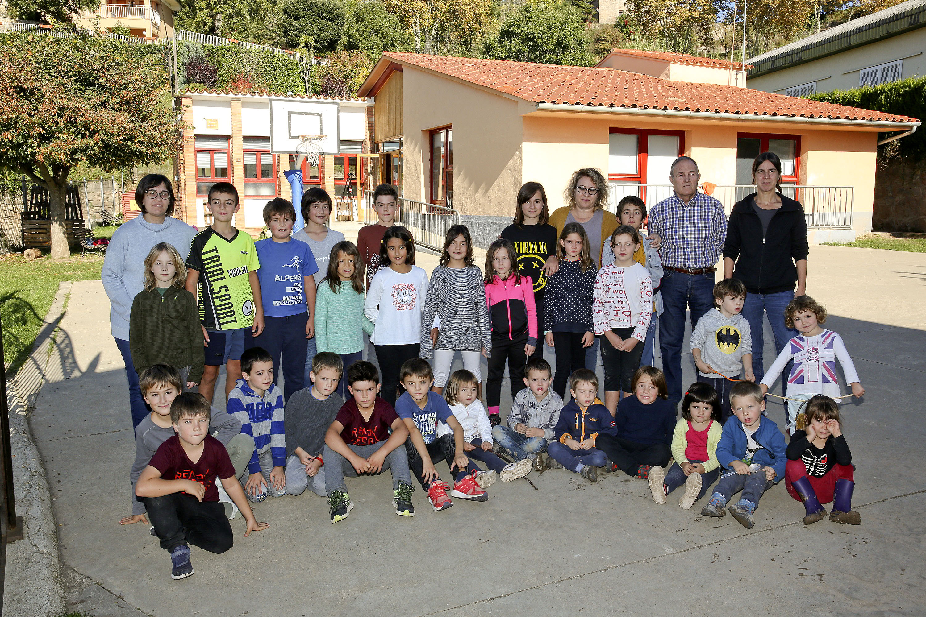 Els 28 alumnes de l'escola d'Alpens, amb les mestres. A la dreta, el primer director del centre, ara jubilat, Joan Crespo, i la directora actual, Meritxell Pujol