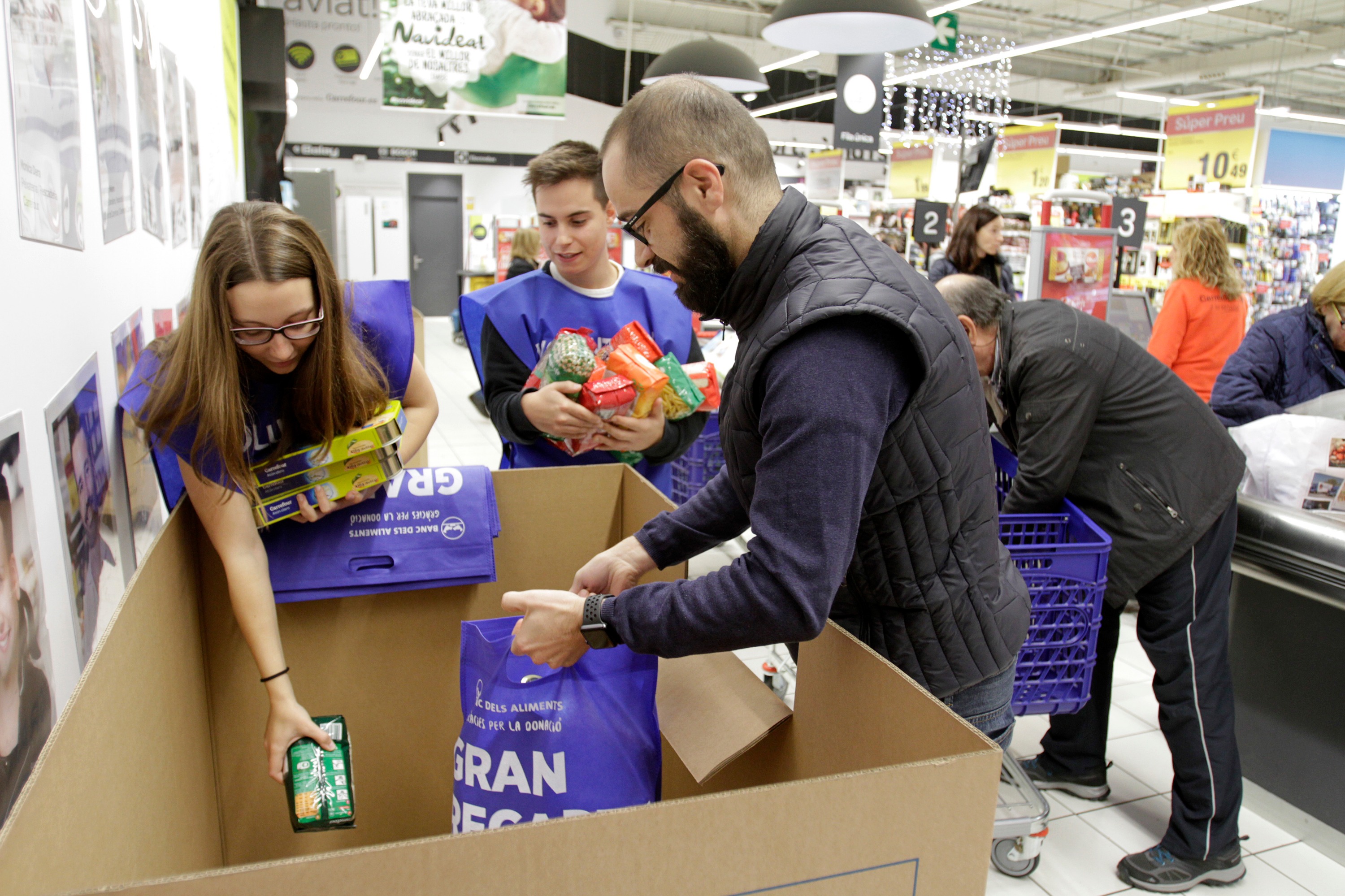 Uns voluntaris distribueixen aliments recollits en un supermercat a Granollers
