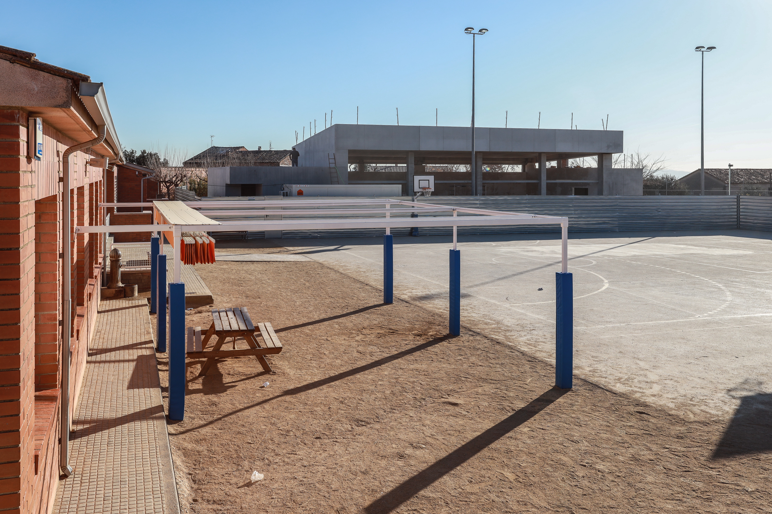 L'edifici s'aixeca entre el pati infantil i la pista esportiva de l'escola