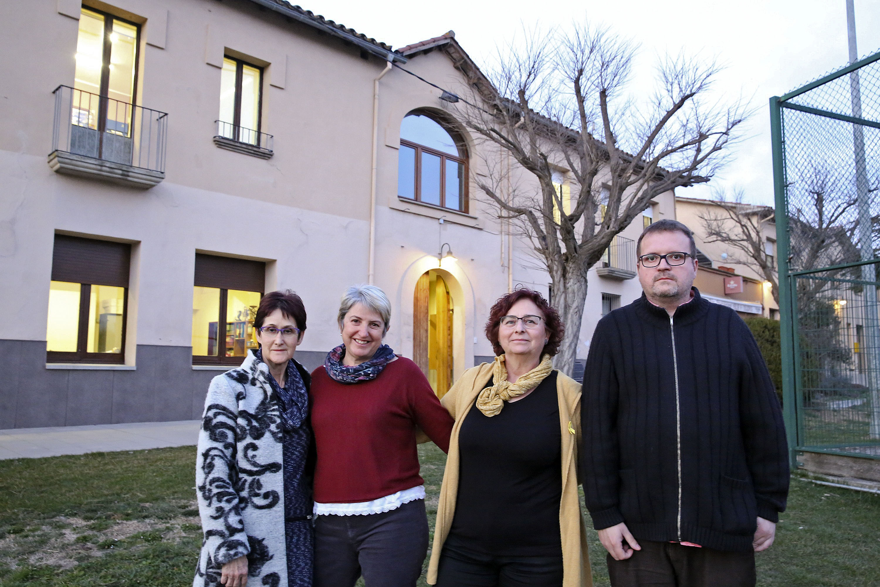Montse Pietx, Isabel Capdevila, Ester Giannoni i Joaquim Riera, del grup Buscant Arrels, davant de l'edifici de l'antiga escola i actual Ajuntament
