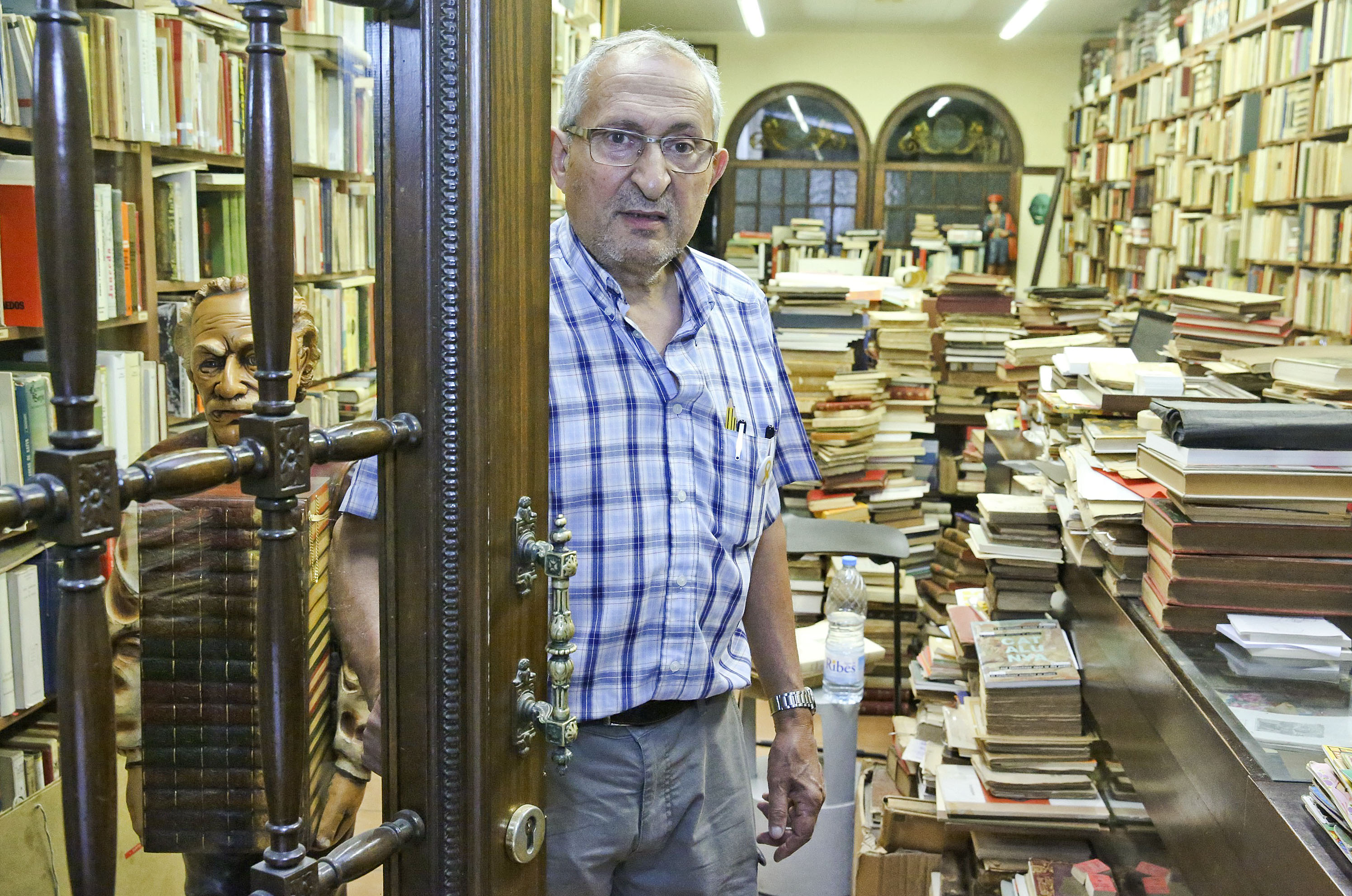 Josep Costa, a l’entrada de la llibreria, amb les vitrines de l’antic menjador al darrere i tot l’escampall de llibres vells
