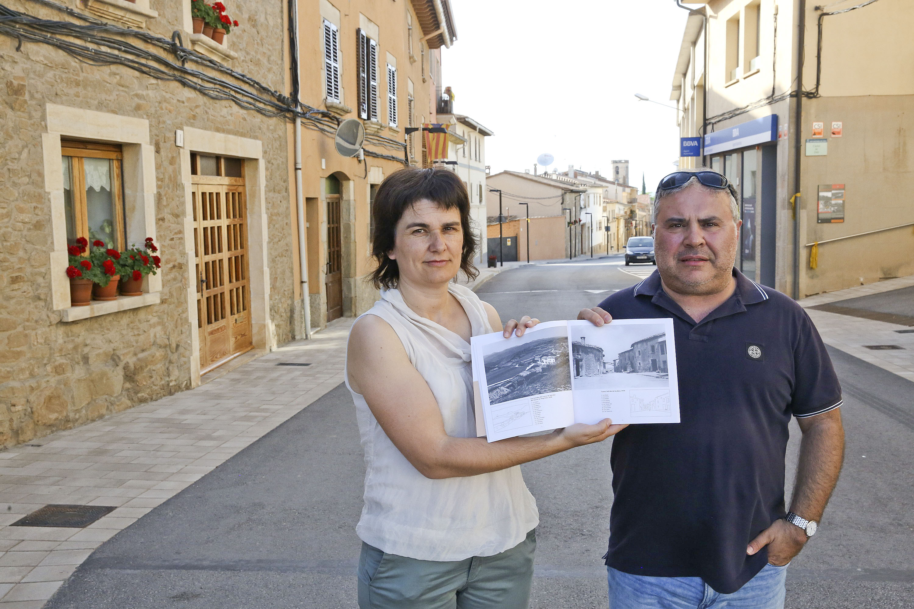 Mercè Sucarrat i Emili Benito, mostrant la pàgina en què surt fotografiat el mateix carrer on es troben