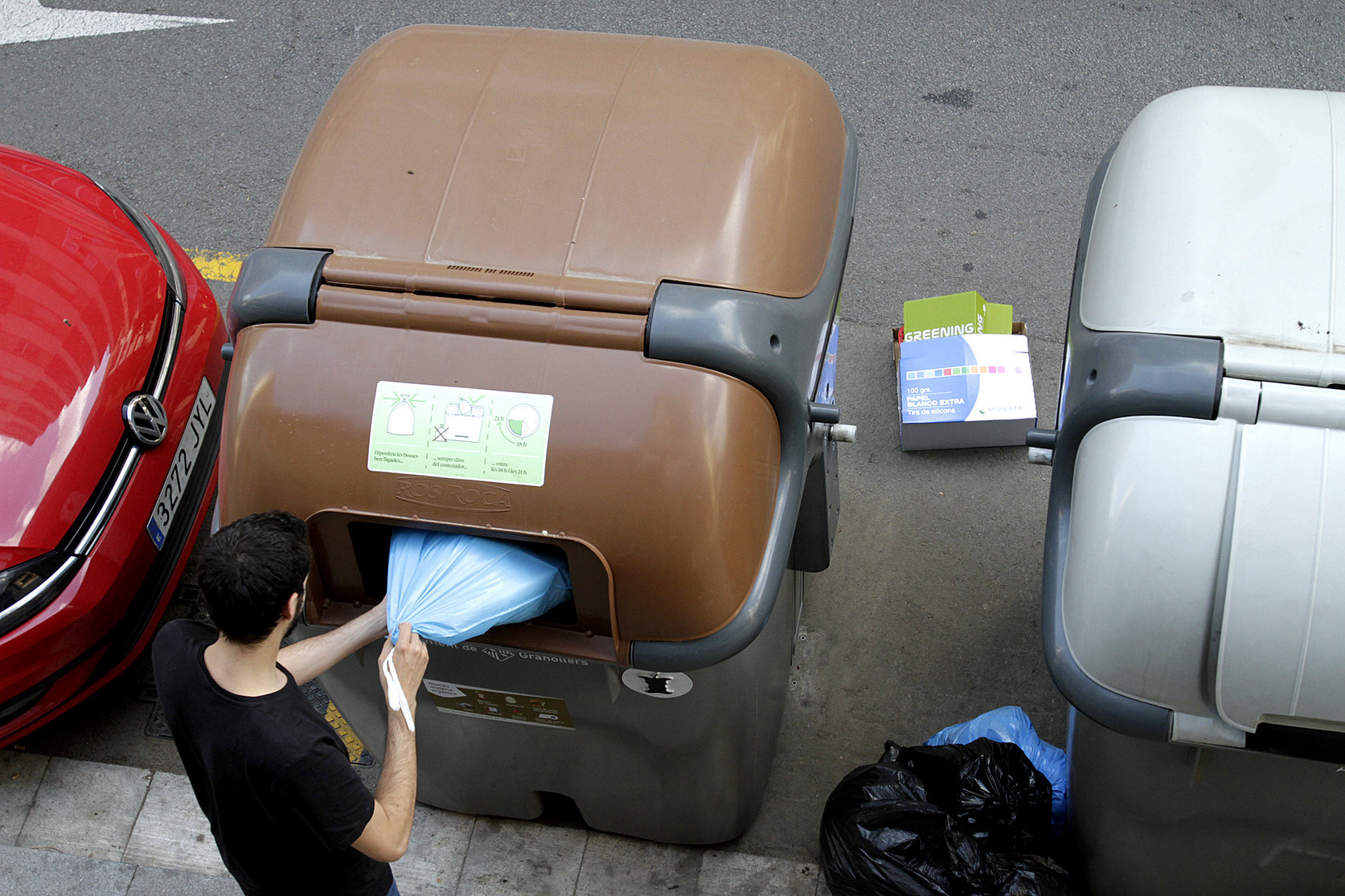 Una persona posant brossa al contenidor d'orgànica