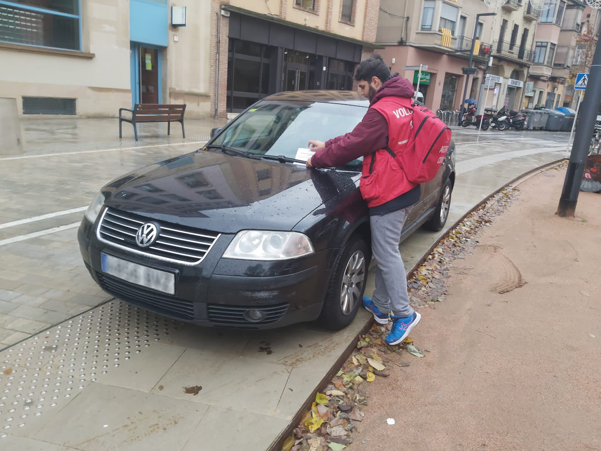 Un agent cívic deixant una nota a un vehicle mal aparcat a la rambla de Vic