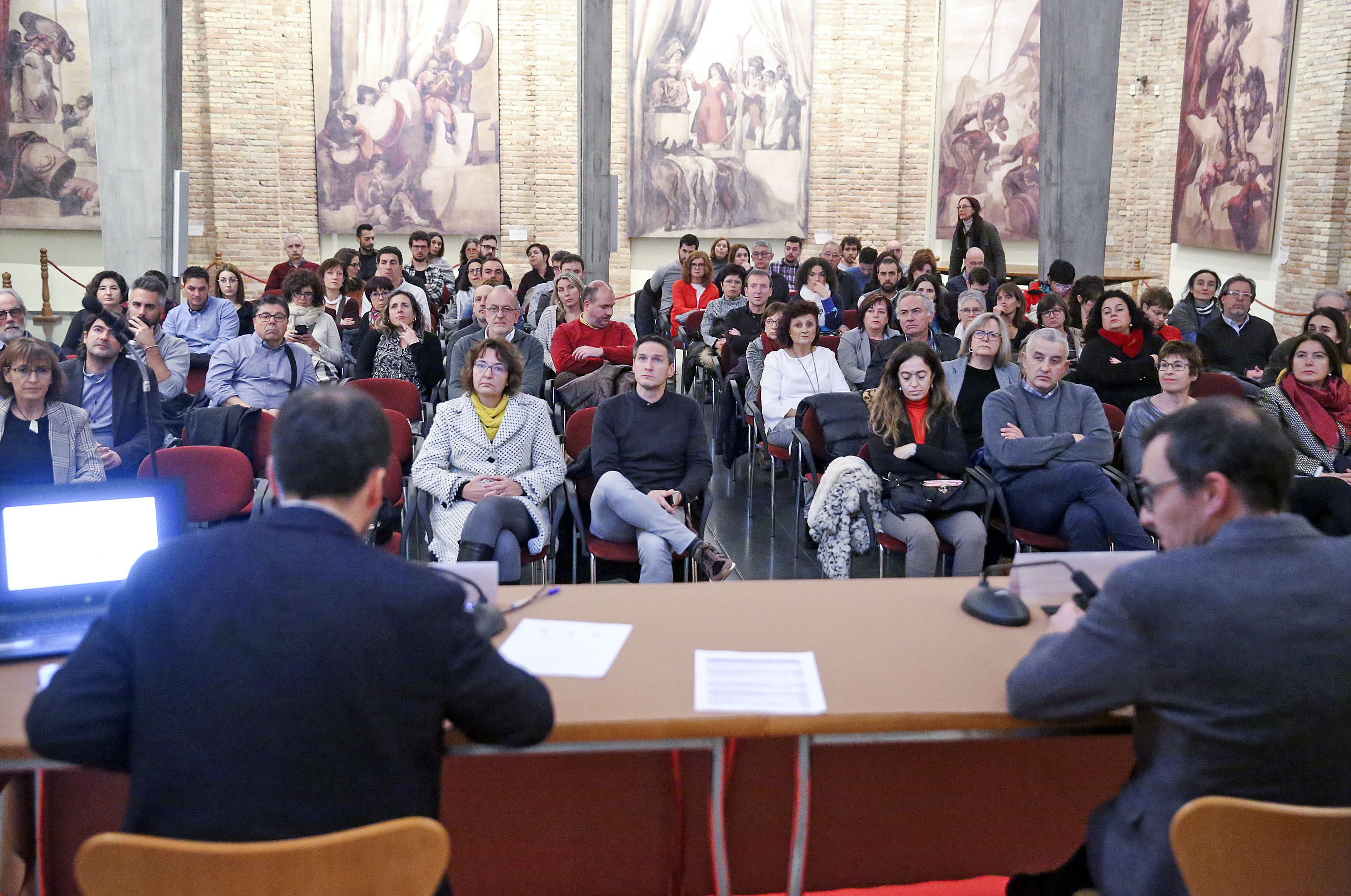 Àlex Montanyà i Carles Banús, d’esquena, adreçant-se al centenar de persones que dijous van assistir a la Nit del Turisme, a la Sala Sert del Sucre de Vic