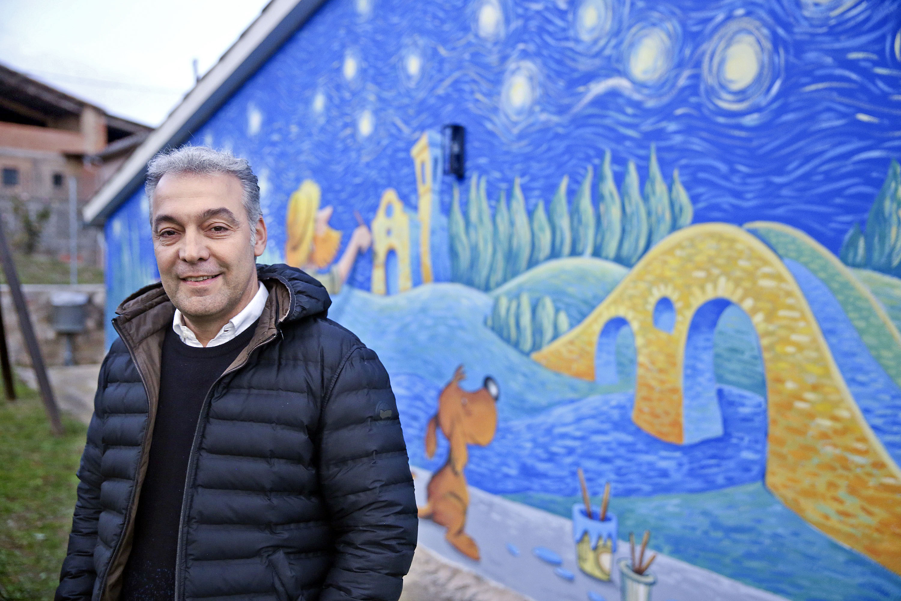 Ramon Padrós, davant d'un mural que ha pintat recentment el dibuixant Subi, darrere la sala polivalent