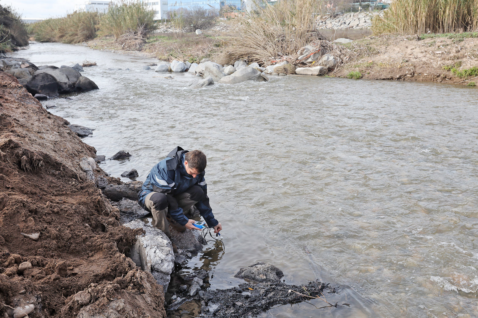 Un inspector de l'ACA recollint mostres d'aigua al riu Besòs