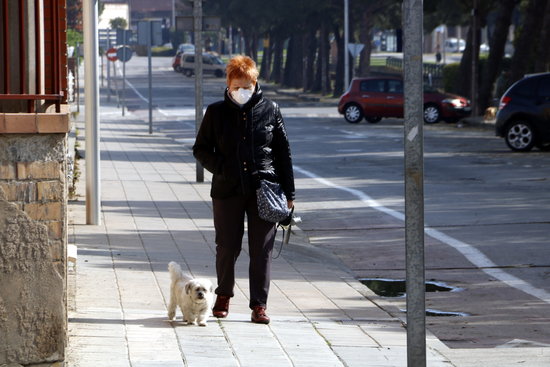 Una senyora amb màscara passejant el seu gos a Mollerussa