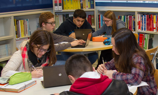 Alumnes treballant en equips en una biblioteca en una imatge d'arxiu