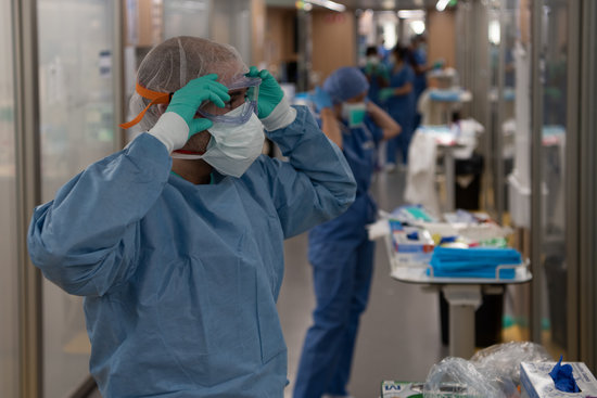 Un professional sanitari es protegeix abans d'estar en contacte amb malalts de coronavirus a l'Hospital Clìnic
