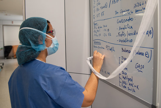 Una professional sanitària pren notes en una pissarra dels tractaments i proves als pacients amb covid-19 a l'Hospital Clínic de Barcelona