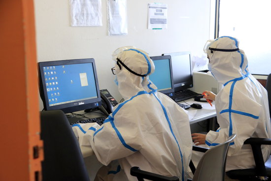 Dues metgesses amb l'equip de protecció individual pel coronavirus consultant informació de pacients amb covid-19 a l'ordinador, a l'Hospital del Mar