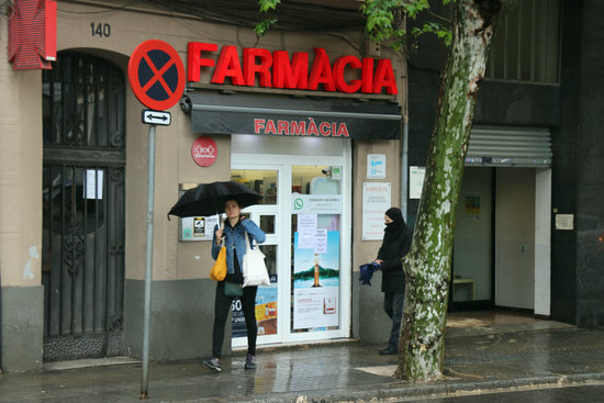 Una persona surt d'una farmàcia de Barcelona sense mascareta aquest dilluns