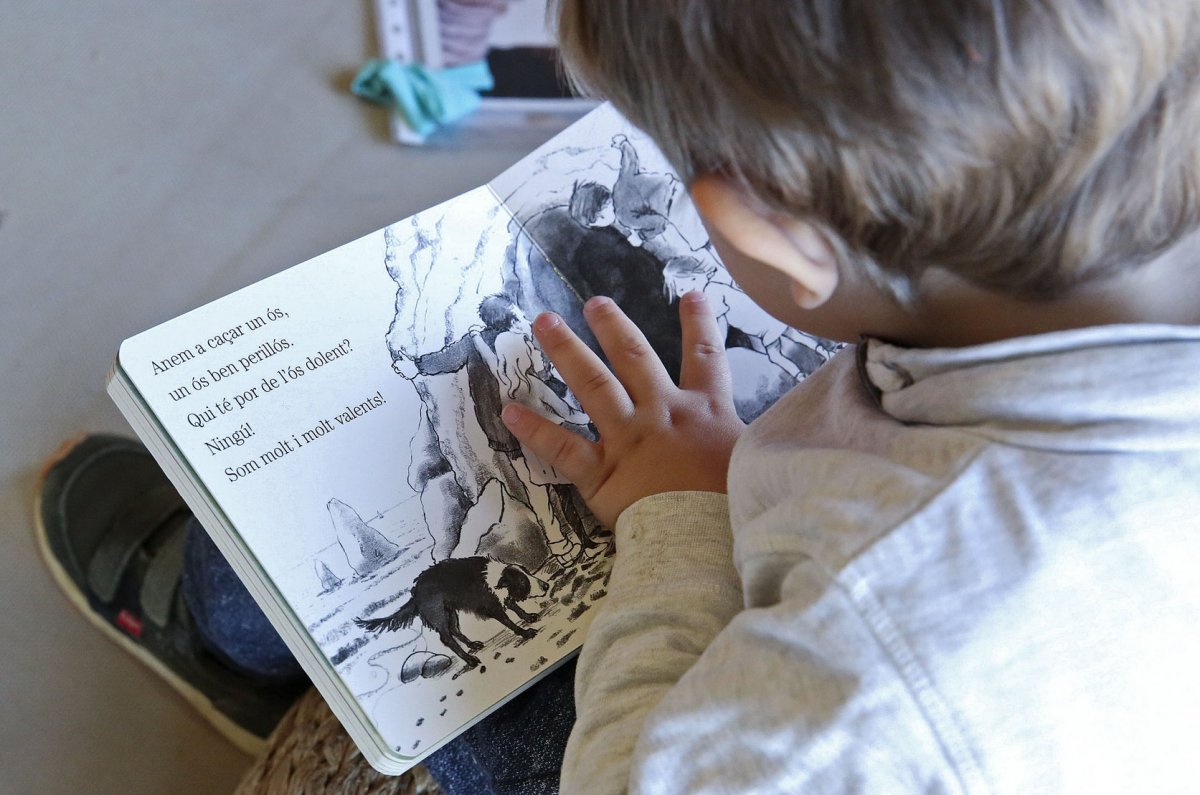 Un infant es mira un conte a l'escola bressol