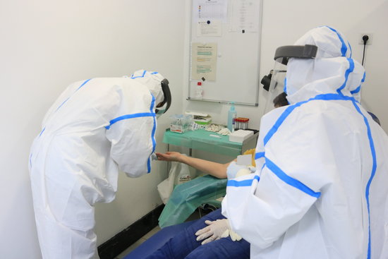 Professionals del CAP Manso en el moment d'extreure una mostra de sang amb una punxada al dit a una participant a l'estudi de seroprevalença del coronavirus a nivell estatal
