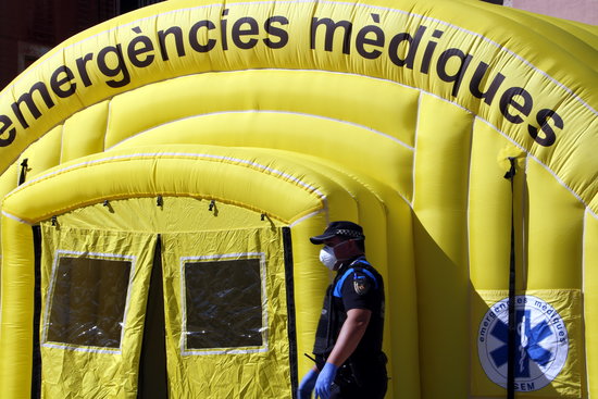 Un agent de la Guàrdia Urbana de Lleida, amb mascareta, passant per davant de la carpa medicalitzada del SEM