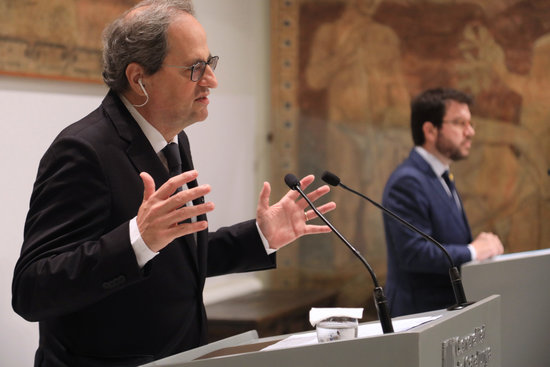 El president de la Generalitat, Quim Torra, amb el vicepresident del Govern, Pere Aragonès, al fons, durant la compareixença per explicar l'estratègia 'Catalunya 2022'