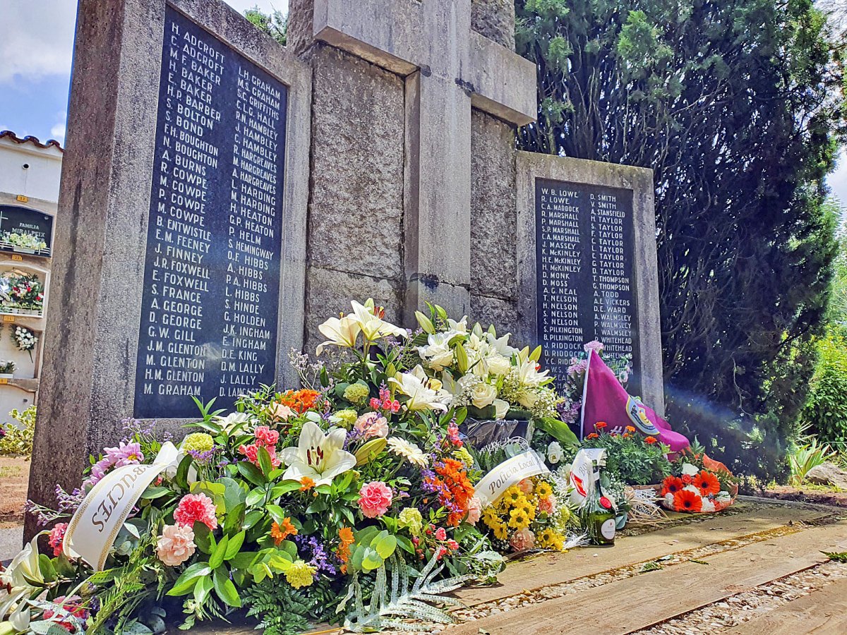 Ofrena floral a la fossa del cementiri d’Arbúcies, amb l’ampolla de Bénédictine i la bandera de Burnley al fons