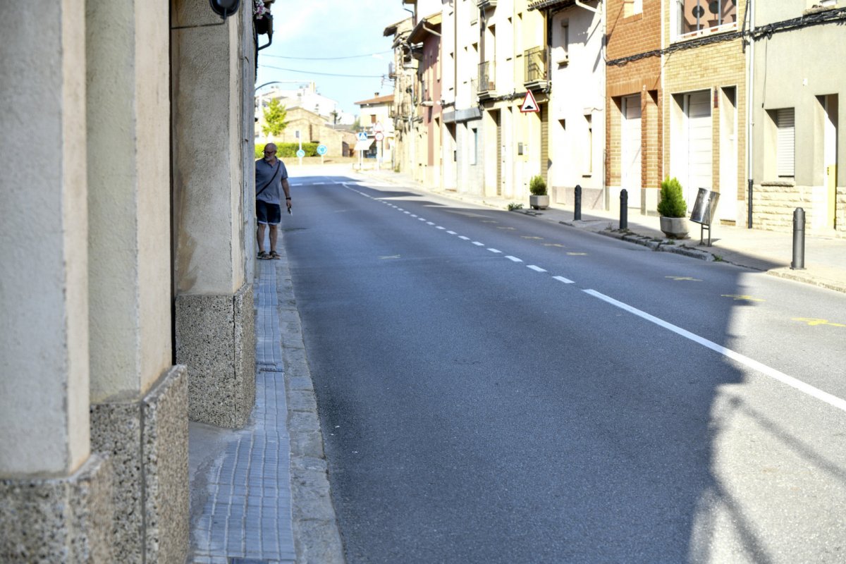 Un vianant camina per l'estreta vorera del carrer Major de Sentfores-La Guixa