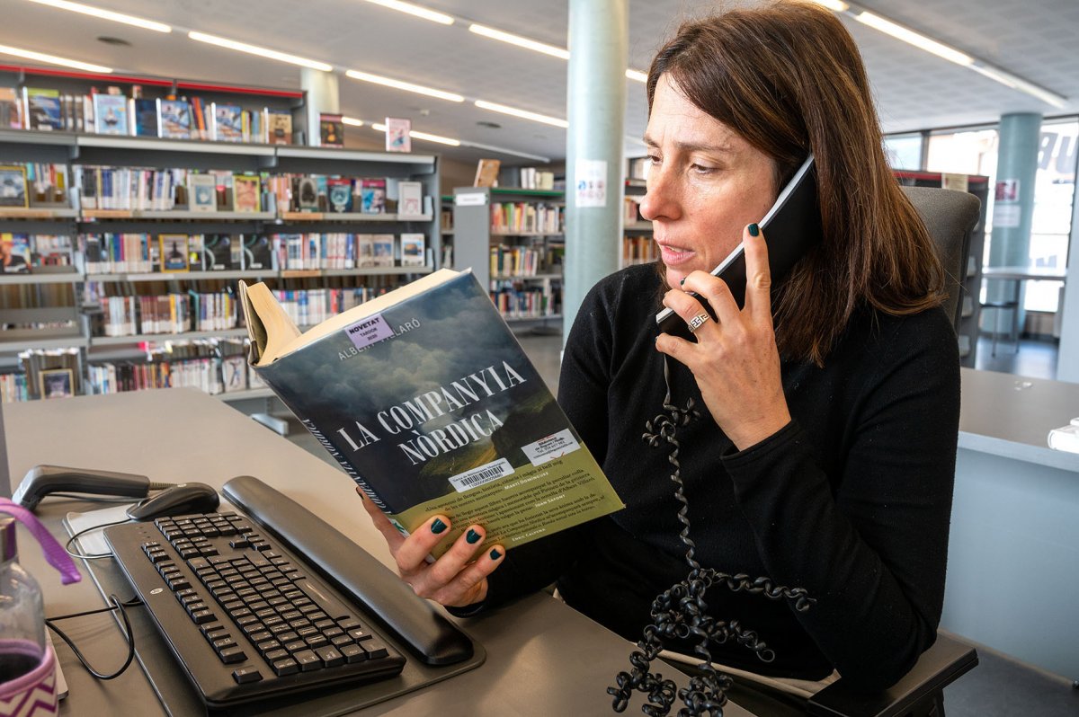 La directora de la biblioteca, Marta Alòs, al telèfon amb un llibre
