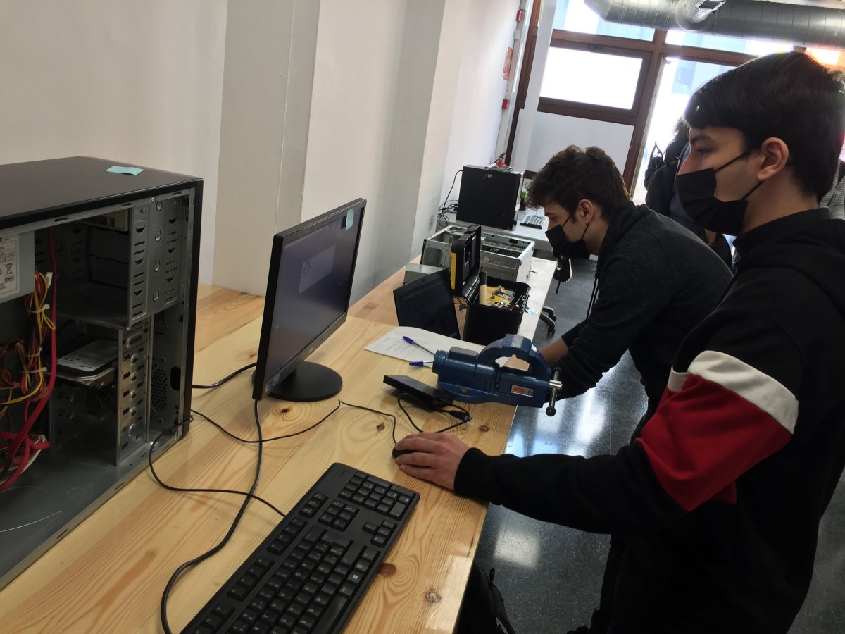 Dos alumnes de l'institut Carles Vallbona fent el buidatge d'un dels ordinadors que ja els han arribat