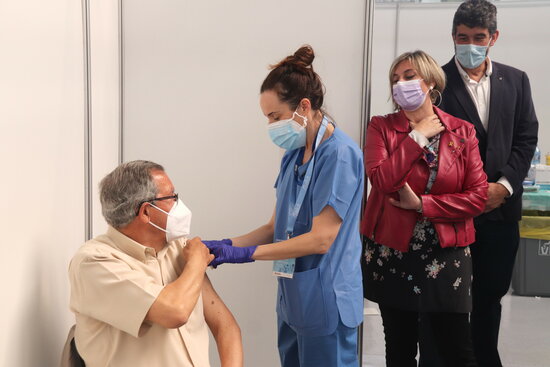 La consellera de Salut, Alba Vergés, mirant com administren una vacuna a un home al punt de vacunació massiva