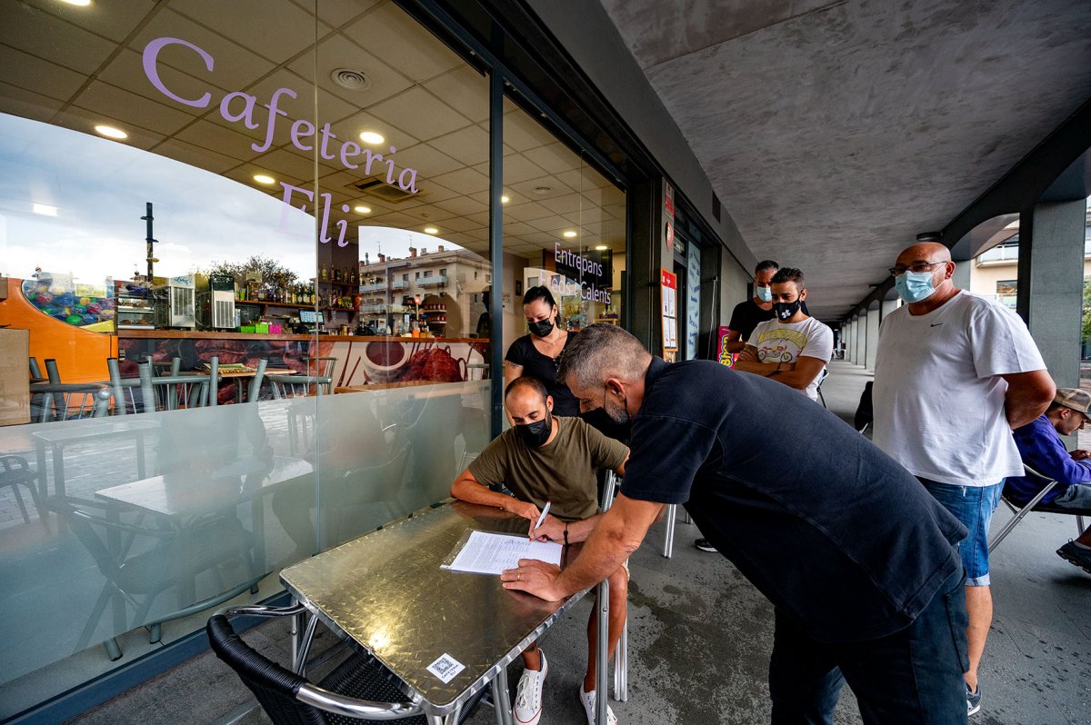 Recollida de signatures en una cafeteria de la plaça de l'Espolsada, a Corró d'Avall