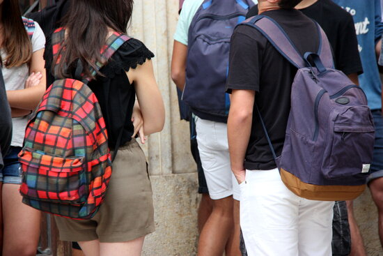 Dos adolescents amb motxilles a l'esquena abans d'entrar a classe