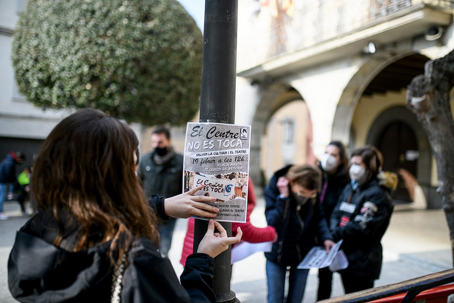 Una de les participants en l’acció de dissabte enganxa un cartell en un fanal de la plaça Major de Sant Quirze