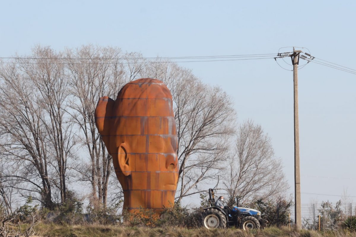 Un tractor passa a pel costat de l'escultura de Jaume Plensa, aquest dimarts al matí