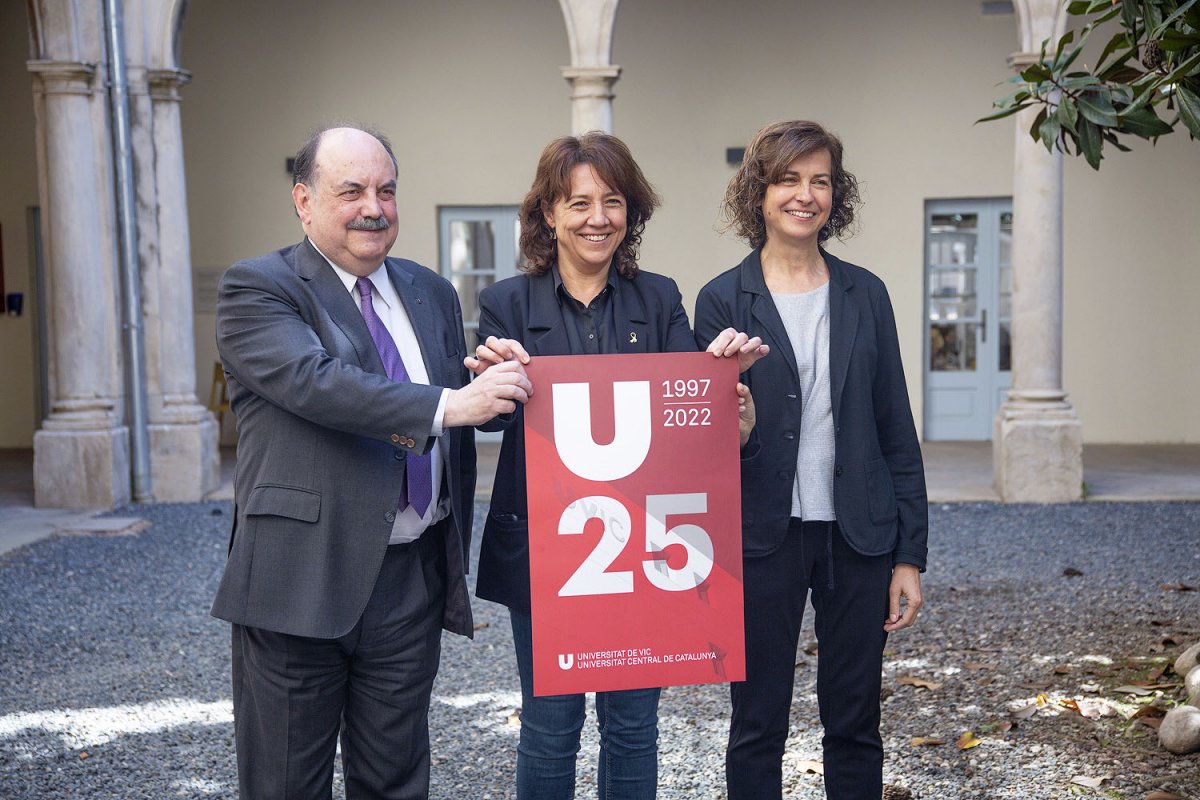 Josep Eladi Baños, Anna Erra i Anna Sabata, amb el cartell dels 15 anys, al pati de la Casa de la Convalsescència