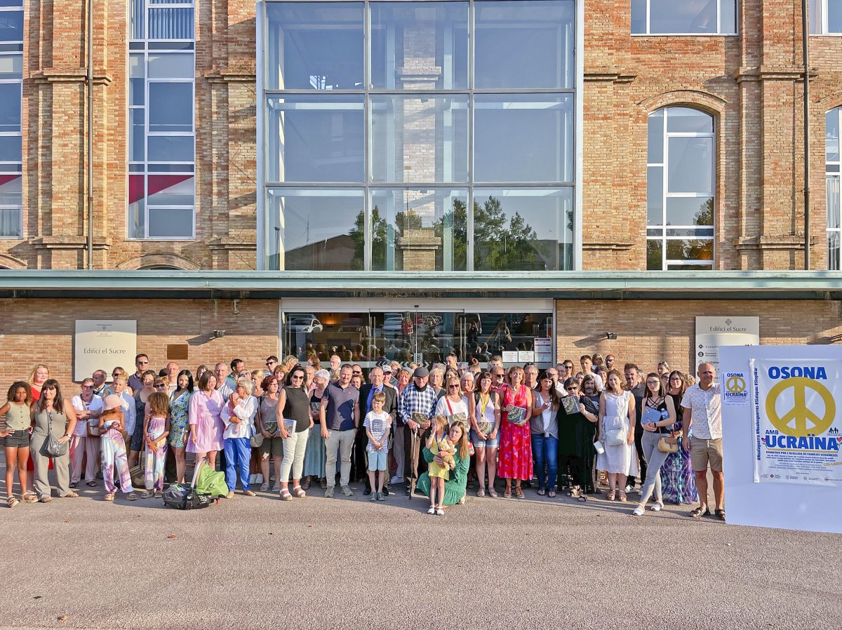 Persones refugiades d'Ucraïna i famílies osonenques d'acollida, representants de l'ONG Osona amb els Nens i del Consell Comarcal, divendres davant l'edifici del Sucre de Vic