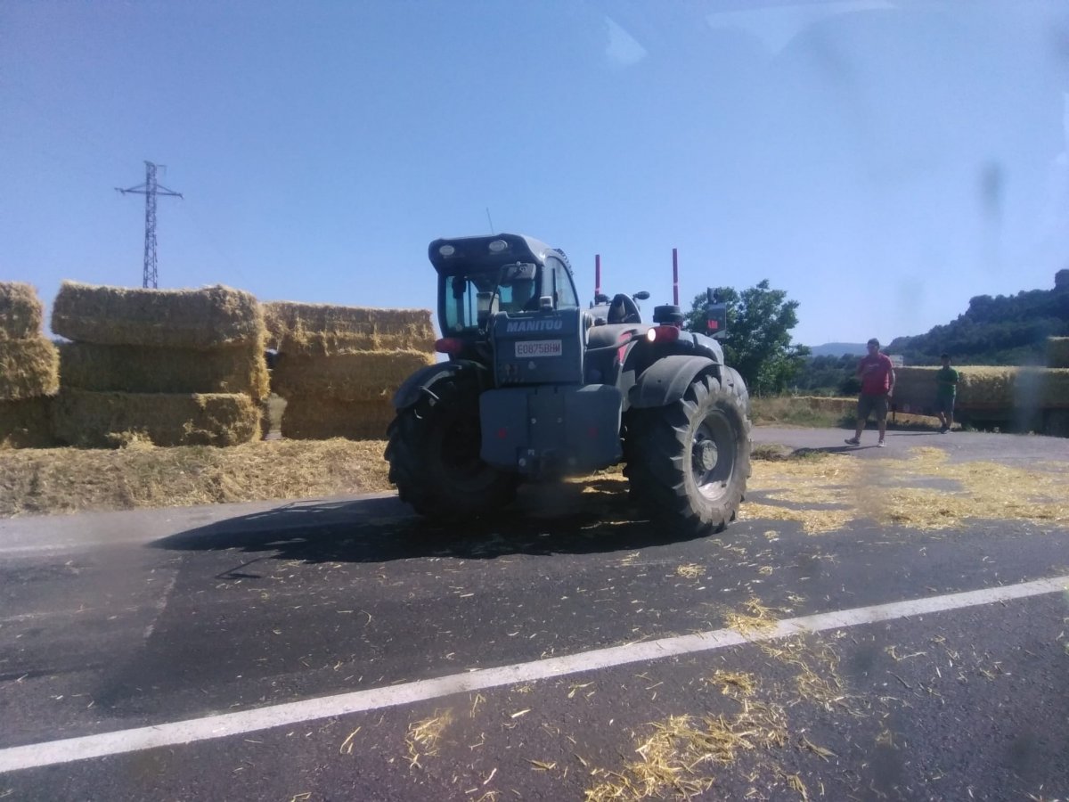 En primer terme el tractor i les bales ja retirades de la calçada. Al fons, a la dreta, el remolc