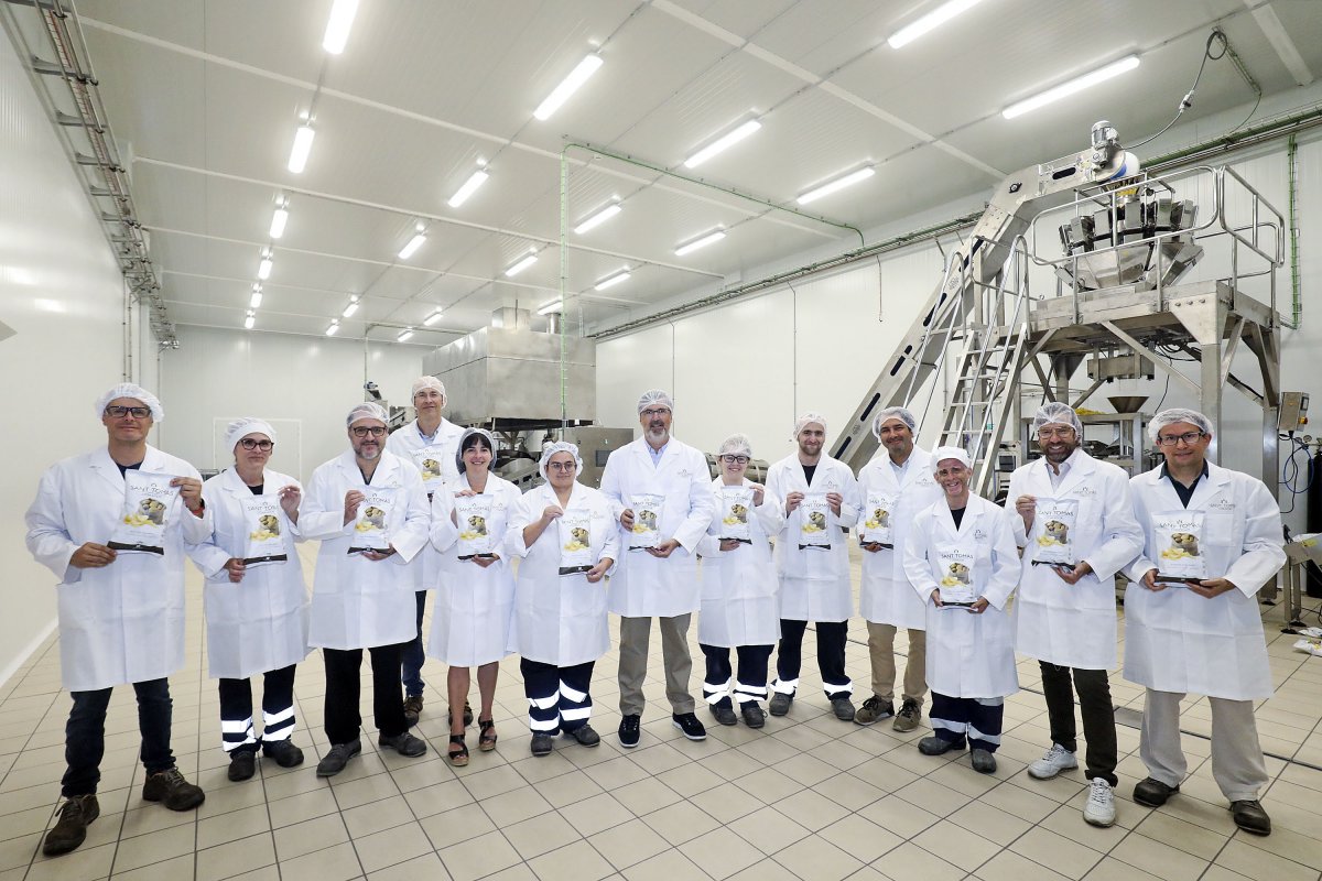 Treballadors de la planta i responsables de Sant Tomàs i el TAC Osona a la planta de producció amb les bosses de 170 grams de patates fregides a les mans