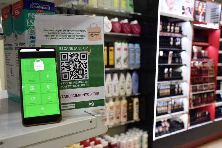 Un mòbil amb l'app oberta en una de les botigues participants