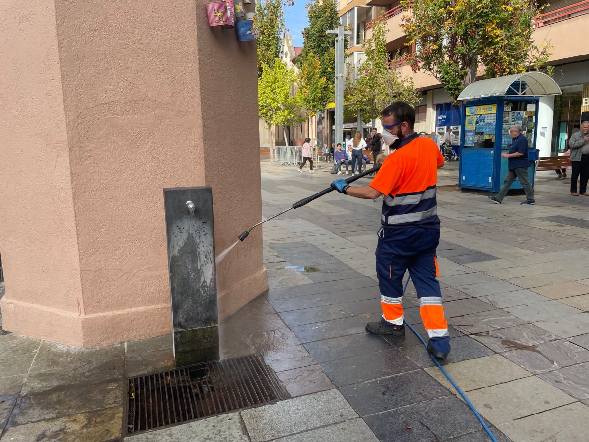 Un operari neteja, aquest dimecres, la font de la plaça Maluquer i Salvador