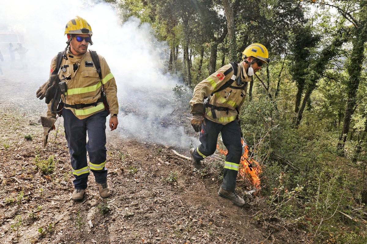 Un bomber fent la crema amb una torxa mentre un altre el vetlla a la finca d'El Muntaner a Sobremunt