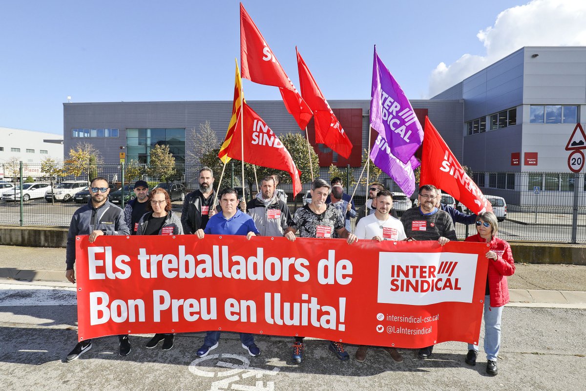 Els quatre treballadors acomiadats, subjectant la pancarta entre altres representants de la Intersindical