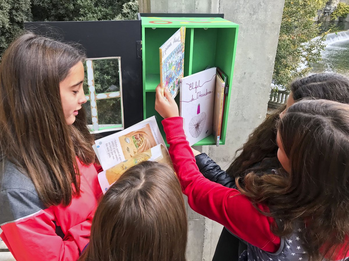 Membres del consistori infantil de Sant Quirze fullejant els llibres de la minibiblioteca de la plaça Bisaura