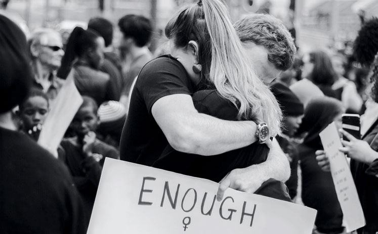 Una parella s'abraça en una manifestació mentre subjecta una pancarta que diu: "Prou és prou"