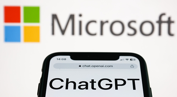 Vista de ChatGPT a la plantalla d'un telèfon mòbil, amb el logo de Microsoft al fons