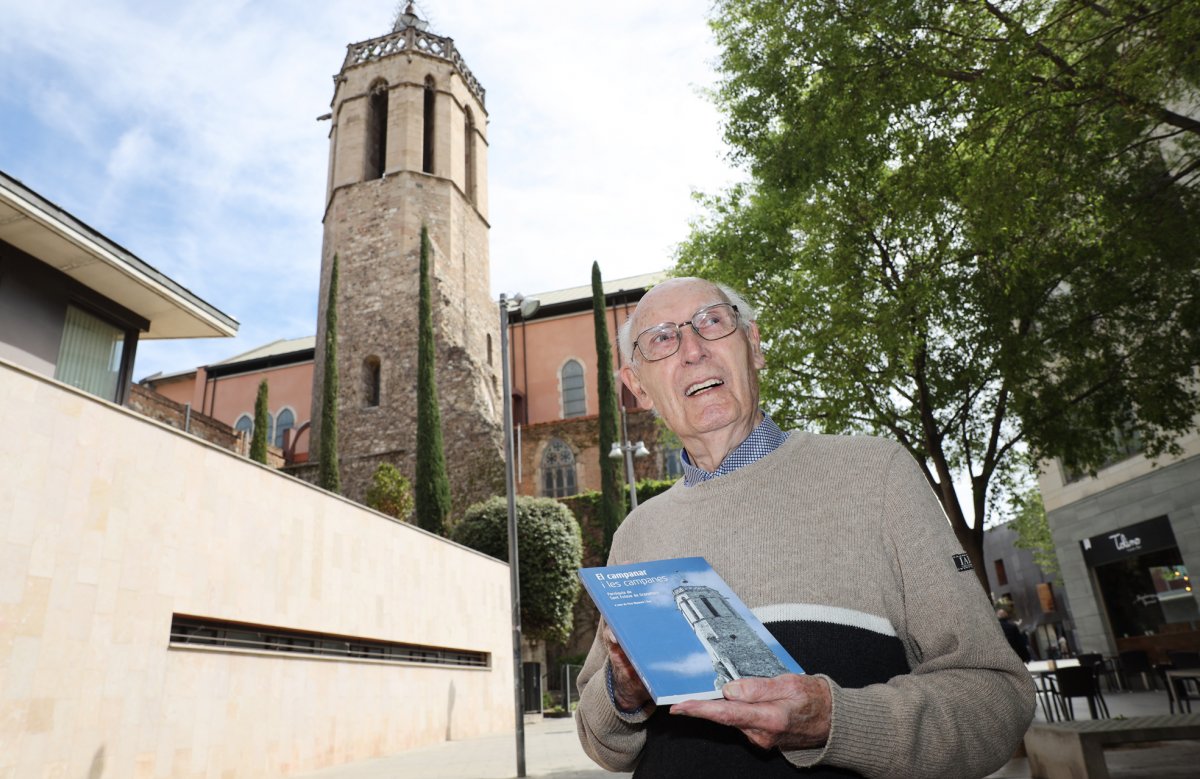 Pere Diumaró amb el llibre amb el campanar de Sant Esteve de fons