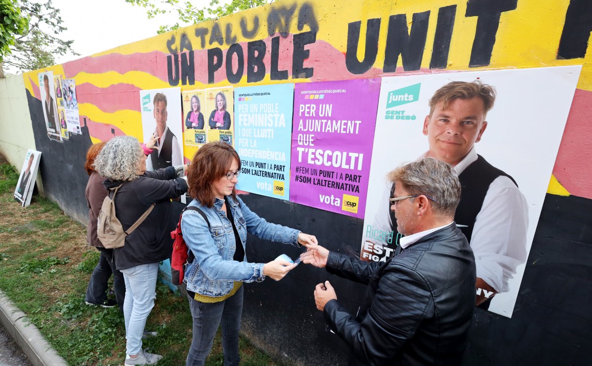 Representants de tres partits polítics col·locant cartells damunt del mur